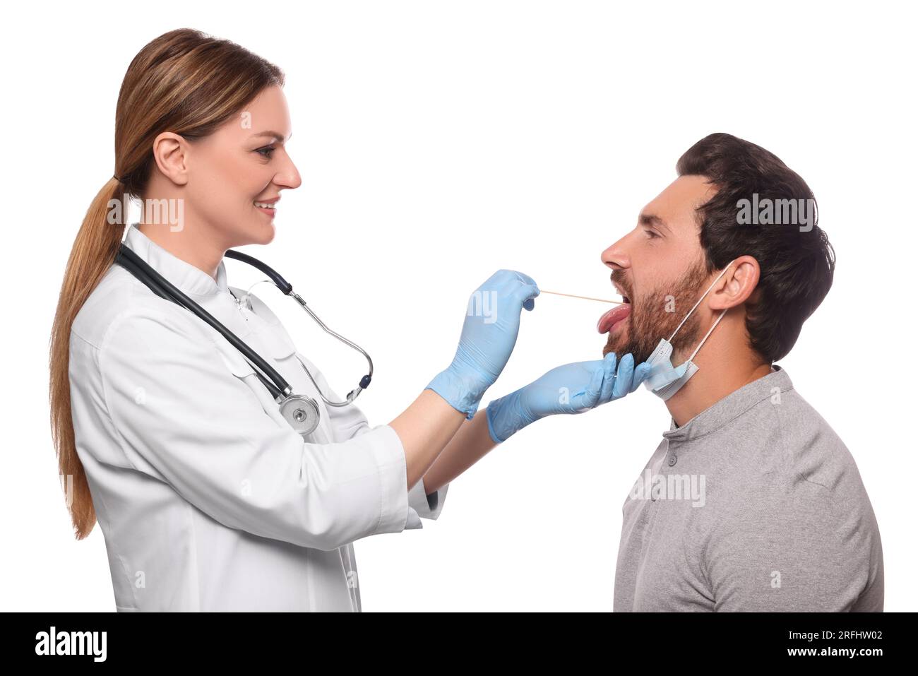 Smiling doctor examining man`s oral cavity with tongue depressor on white background Stock Photo